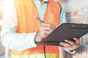 a compliance training provider in high-vis gear writing on a clipboard that holds a compliance checklist
