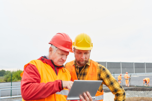 two construction workers digitally managing compliance tickets on a construction site