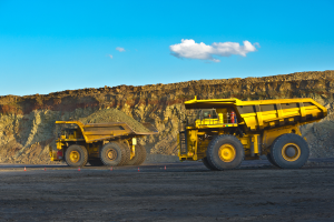 two yellow haul trucks driving across a construction site in Australia
