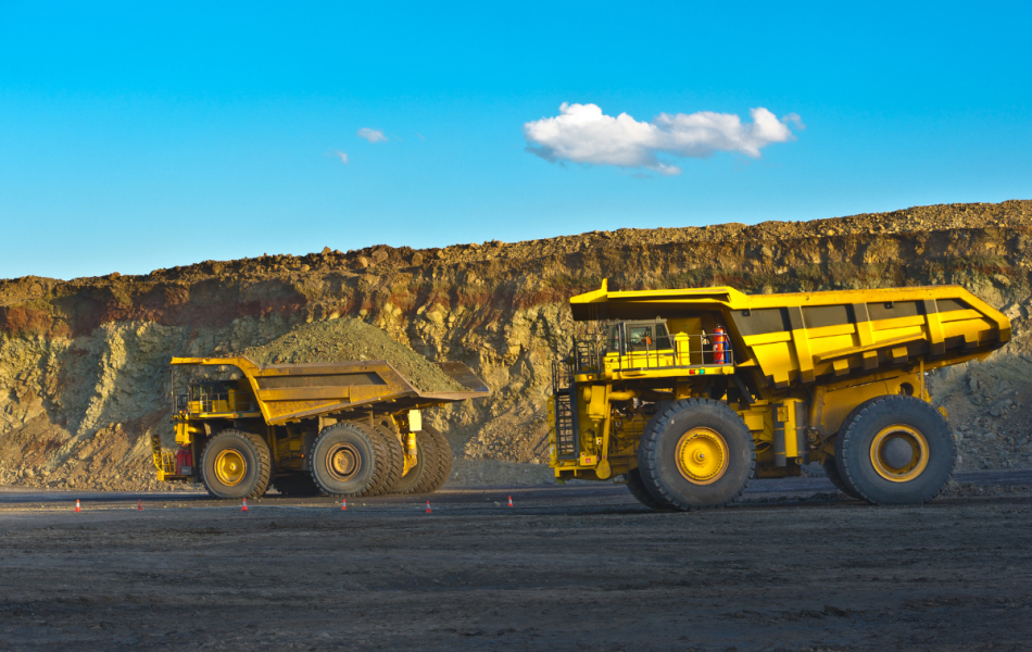 two yellow haul trucks driving across a construction site in Australia
